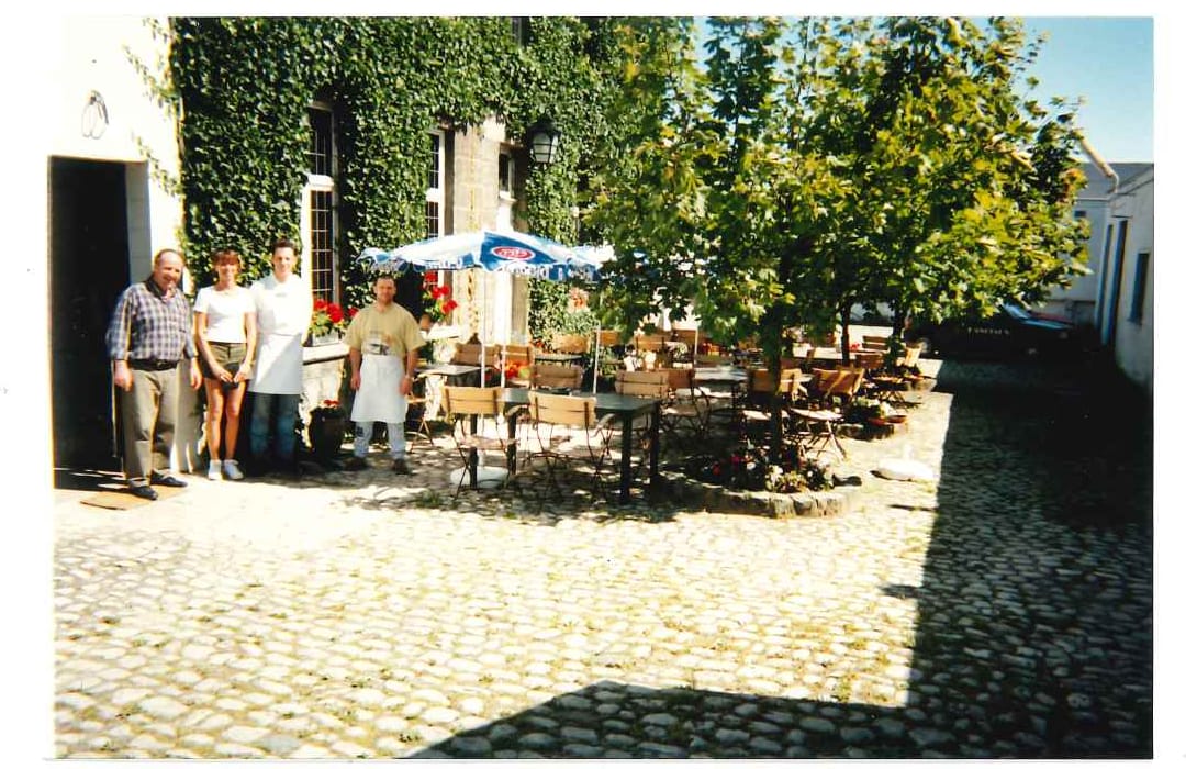 La cour pavée et la terrasse sous la façade couverte de lierre